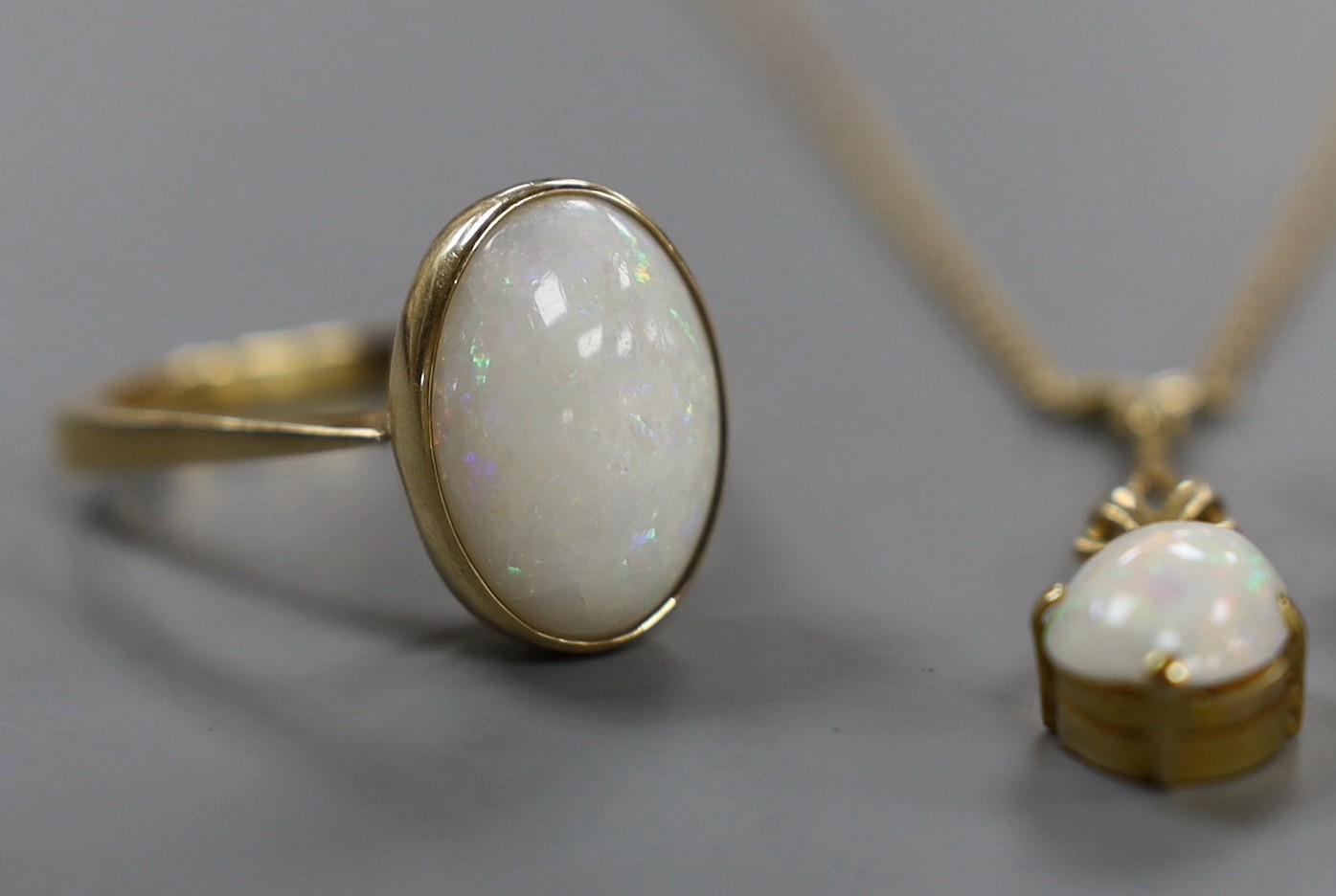 A 750 yellow metal and oval cabochon white opal set ring, size U/V, gross weight 6.2 grams, together with a pair of yellow metal and opal set ear clips and a similar pendant necklace.